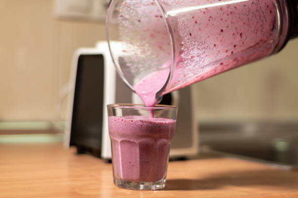 Woman pouring fruit smoothie into a glass. healthy diet concept